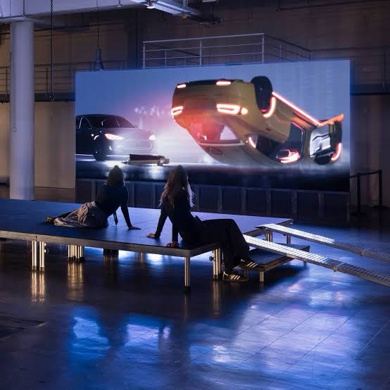 Immersive gallery at ArtScience Museum with dark blue nocturnal lighting and corporate signage for Lawrence Lek’s NOX: Confessions of a Machine.